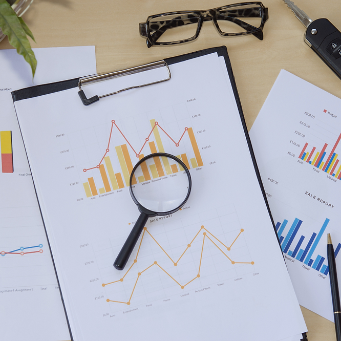 Magnifying glass on printed employee turnover charts and reports on a desk.