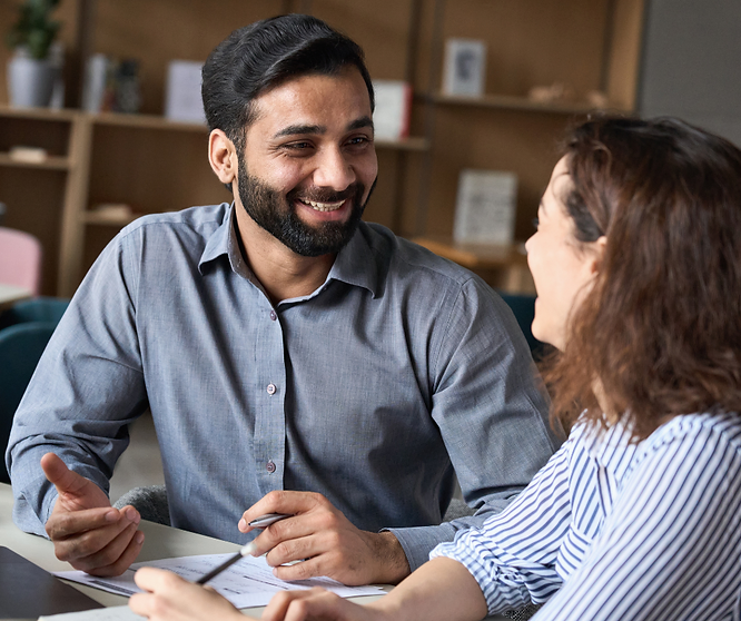 Two employees having a performance review discussion at a desk with paperwork.