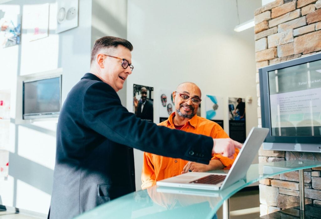 Two men discussing laptop details in an office.